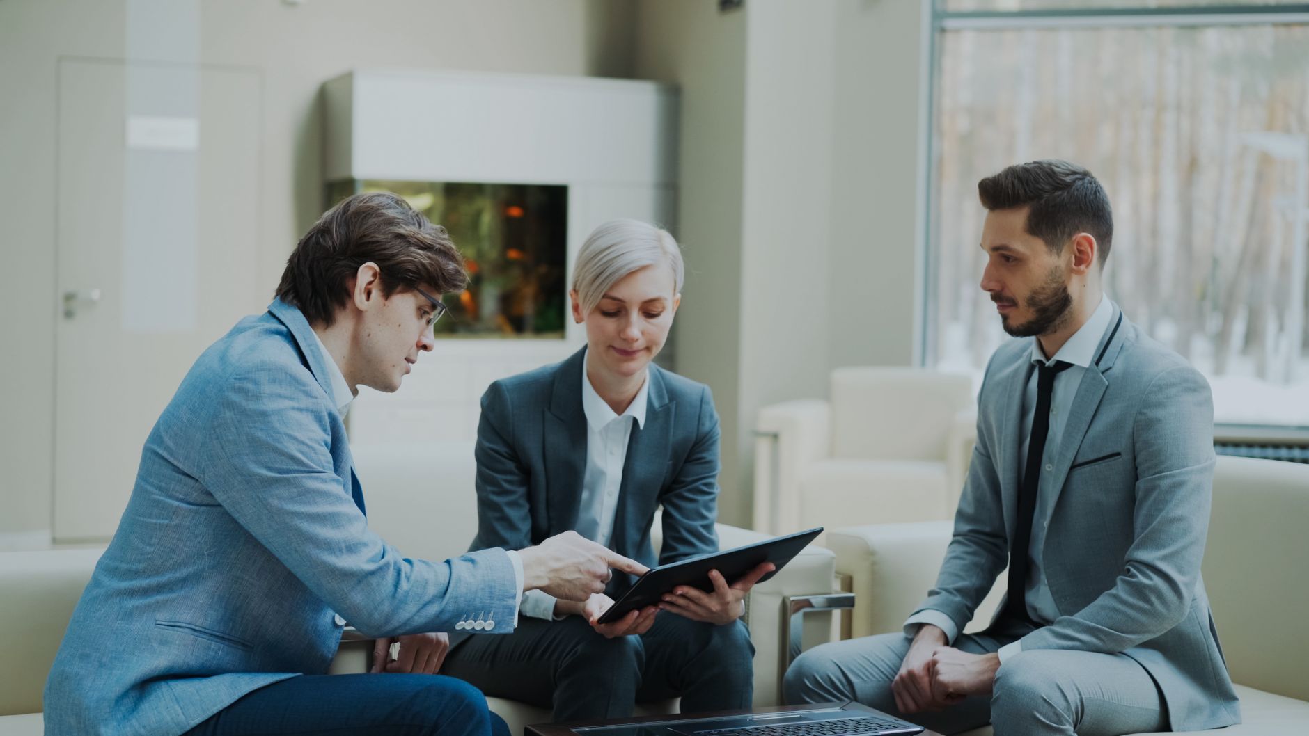 Client consultation and profiling — Three professionals engaging in a business meeting in a modern office setting.
