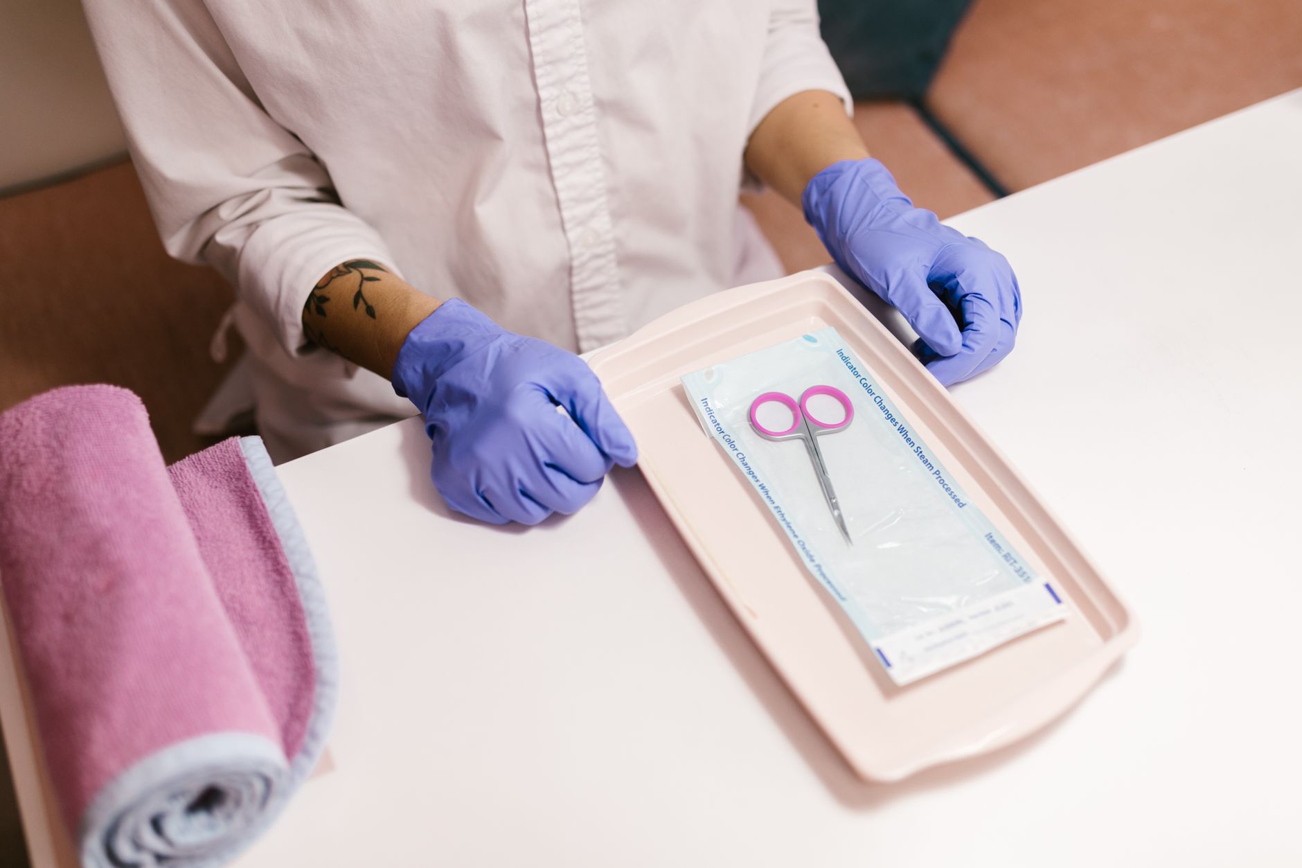 Implement health, safety, and hygiene — Nail technician with gloves preparing tools for a manicure session. focus on hygiene and professionalism.