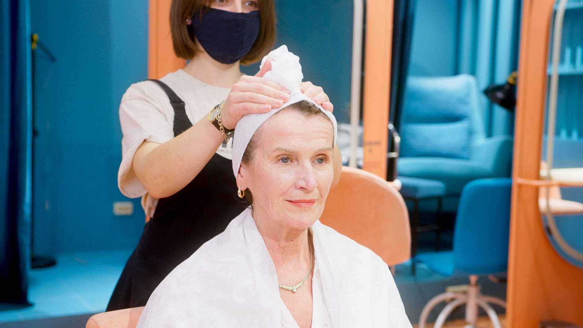 Implement health, safety and hygiene — A senior woman is pampered with a hair treatment in a salon, highlighting the professional care provided.