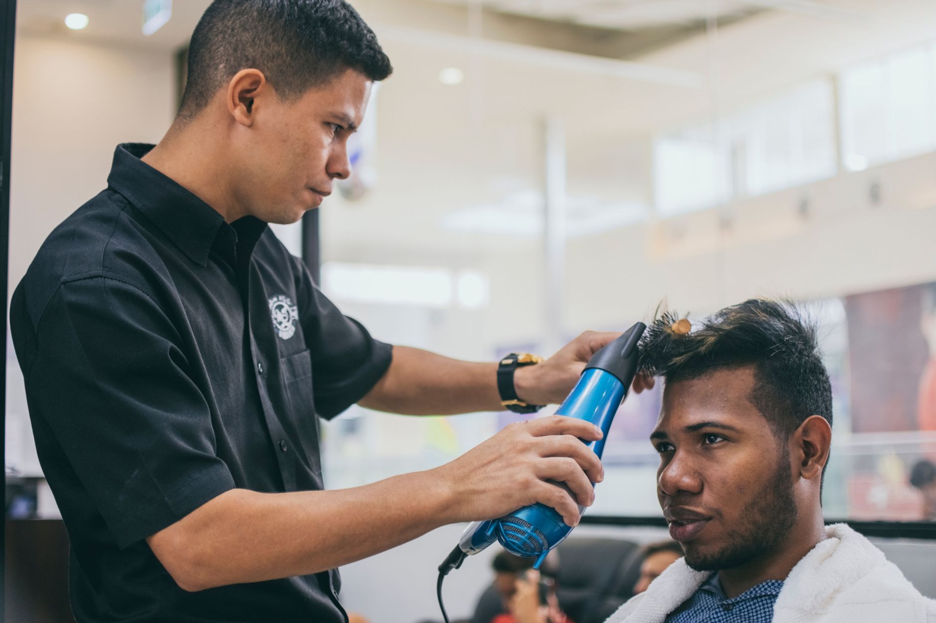 Hair Science — A focused barber styles a client's hair in a modern barbershop setting.