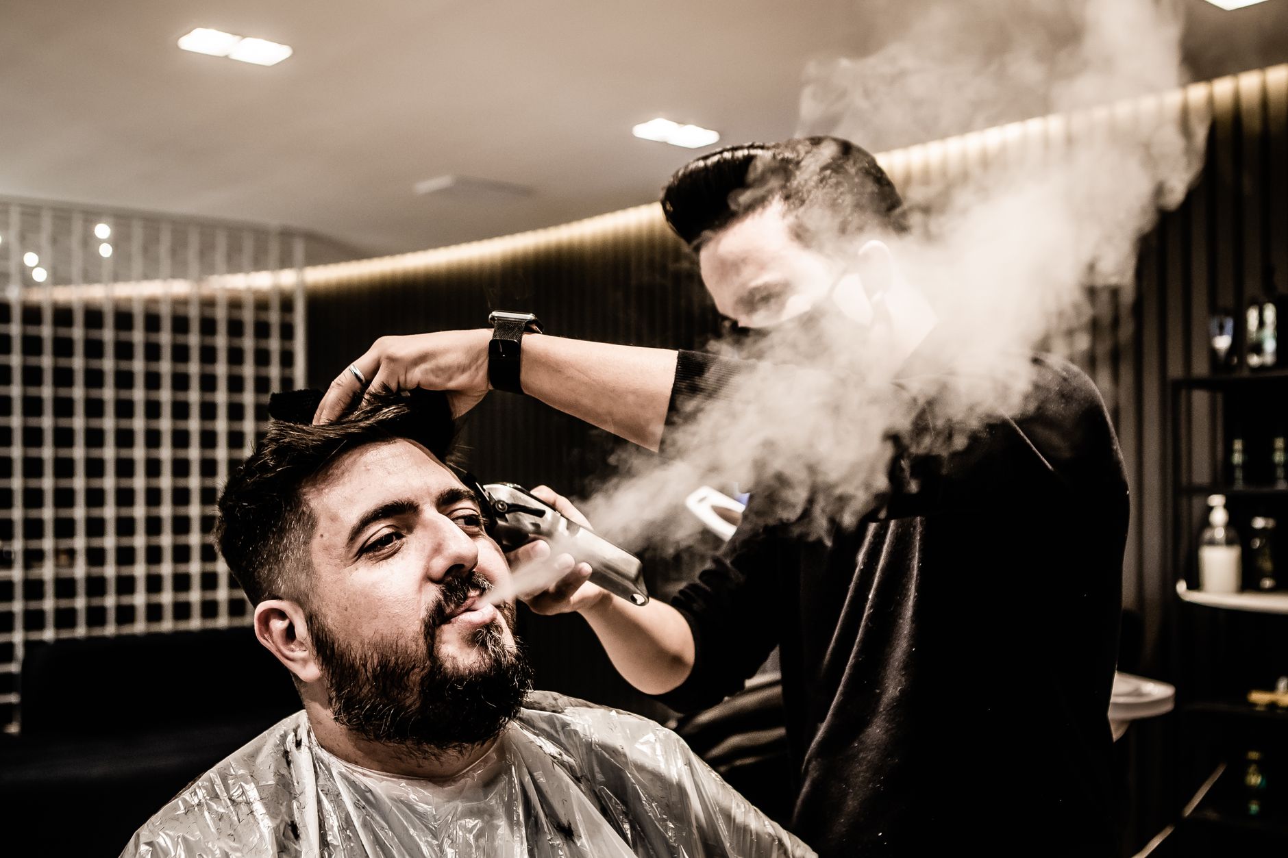 Blow-dry and finish hair — Barber styling a client's hair with steam in a contemporary barbershop setting.