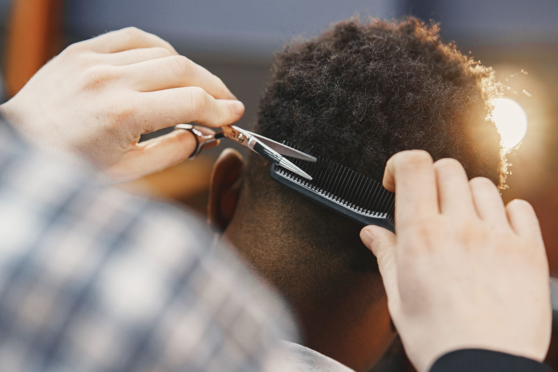 Advanced Hair Science — Close-up of a professional barber trimming an afro hairstyle with scissors and comb.