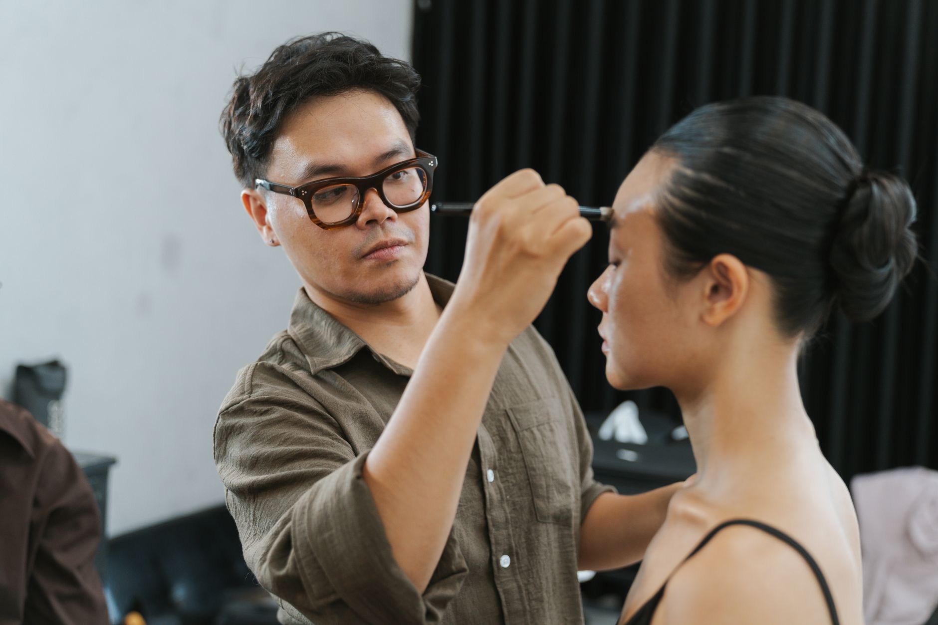Creatively perm hair — A makeup artist carefully applies makeup to a model in an indoor setting, showcasing professional styling.