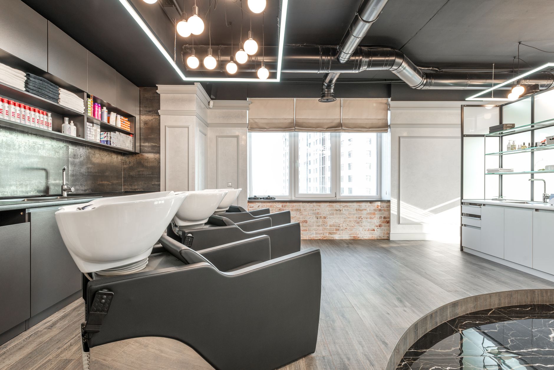 Advise on products and services — Black backwash chairs with sinks placed in modern spacious beauty salon with window and arrangement of cosmetology supply on shelves