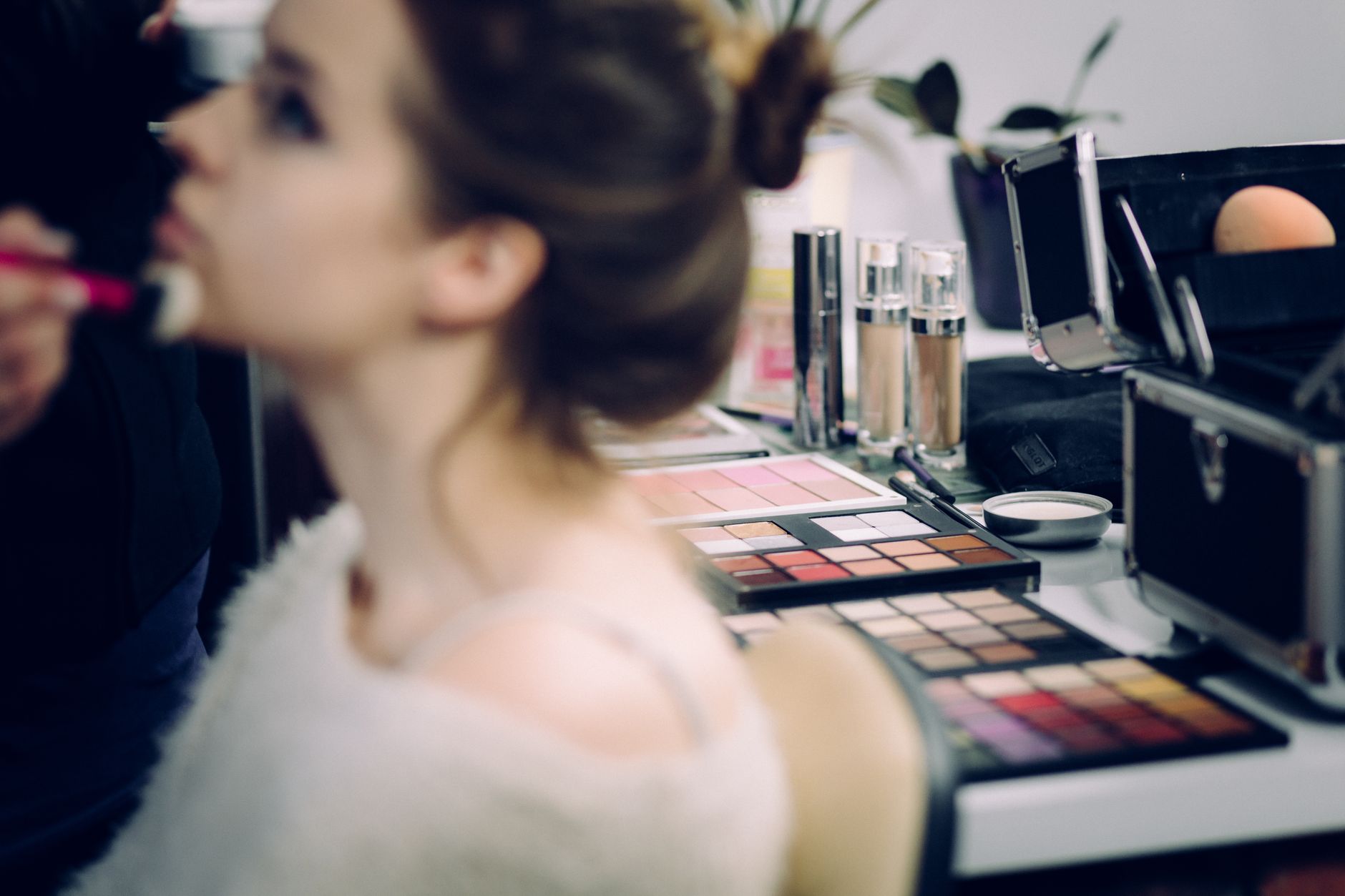 Promotional activities — A woman receiving professional makeup in a studio with various cosmetics in focus.