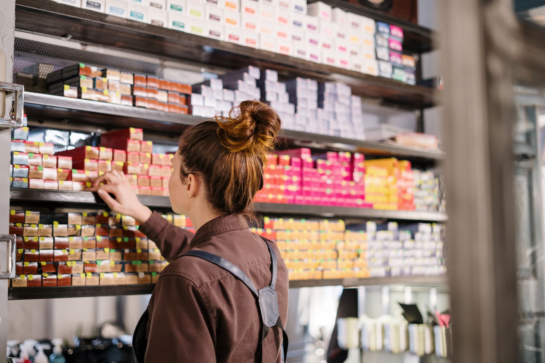 Creatively colour and lighten hair — Hairdresser choosing hair dye from organized shelves in a beauty salon.