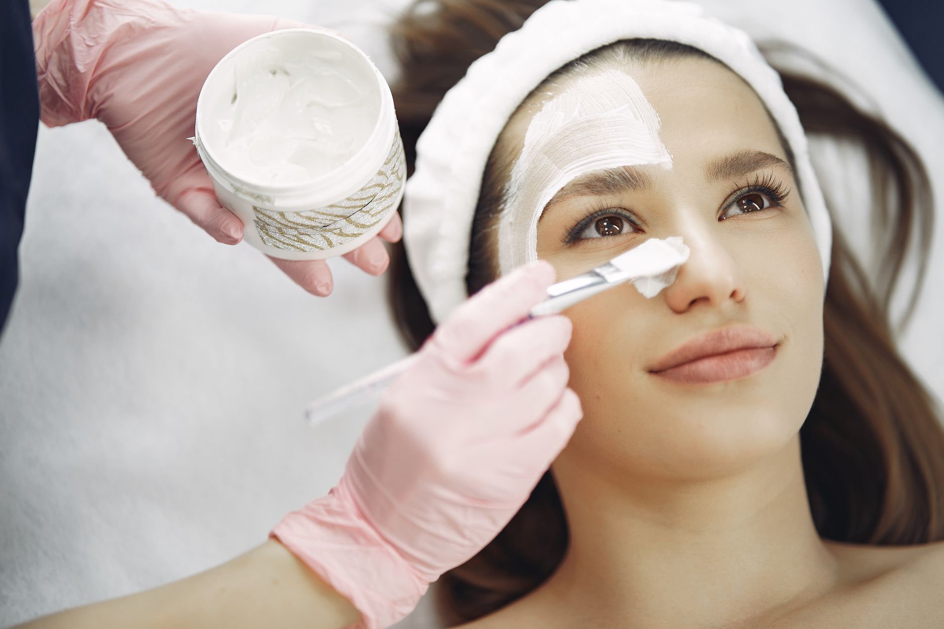 Facial electrotherapy — Close-up of a woman receiving a facial treatment at a spa with a cream mask applied using a brush.