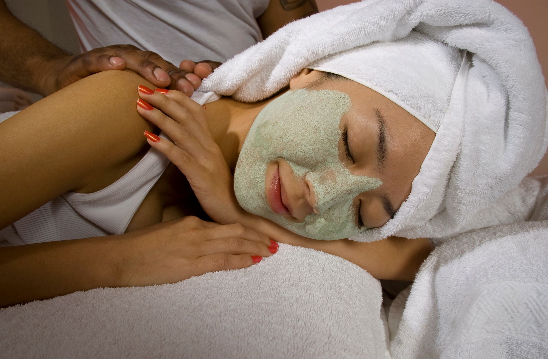 Body wrap treatments — A woman enjoying a rejuvenating facial mask and massage at a spa for relaxation and skincare.