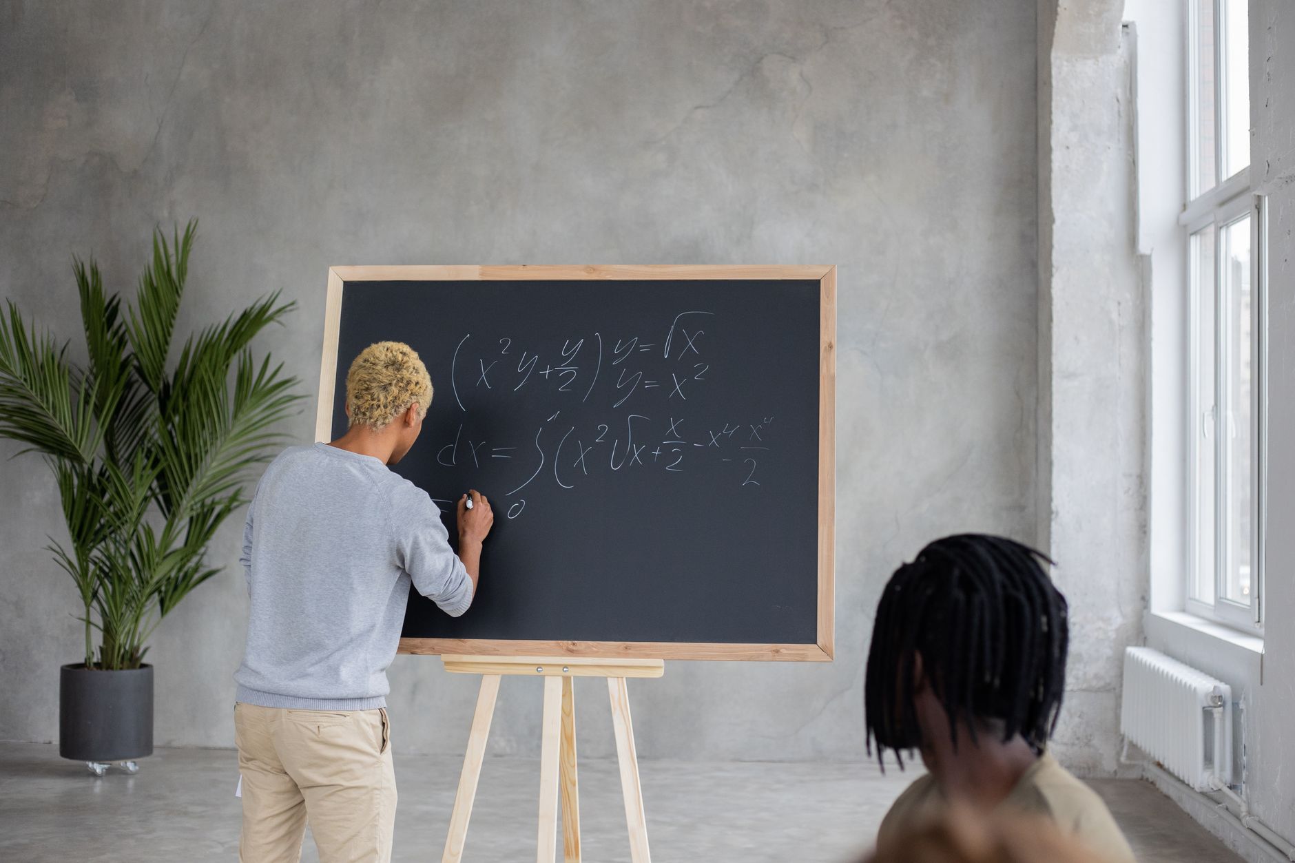 Client consultation and profiling — Unrecognizable african american male student writing mathematical formulas on chalkboard while studying in classroom with faceless black classmate during lesson